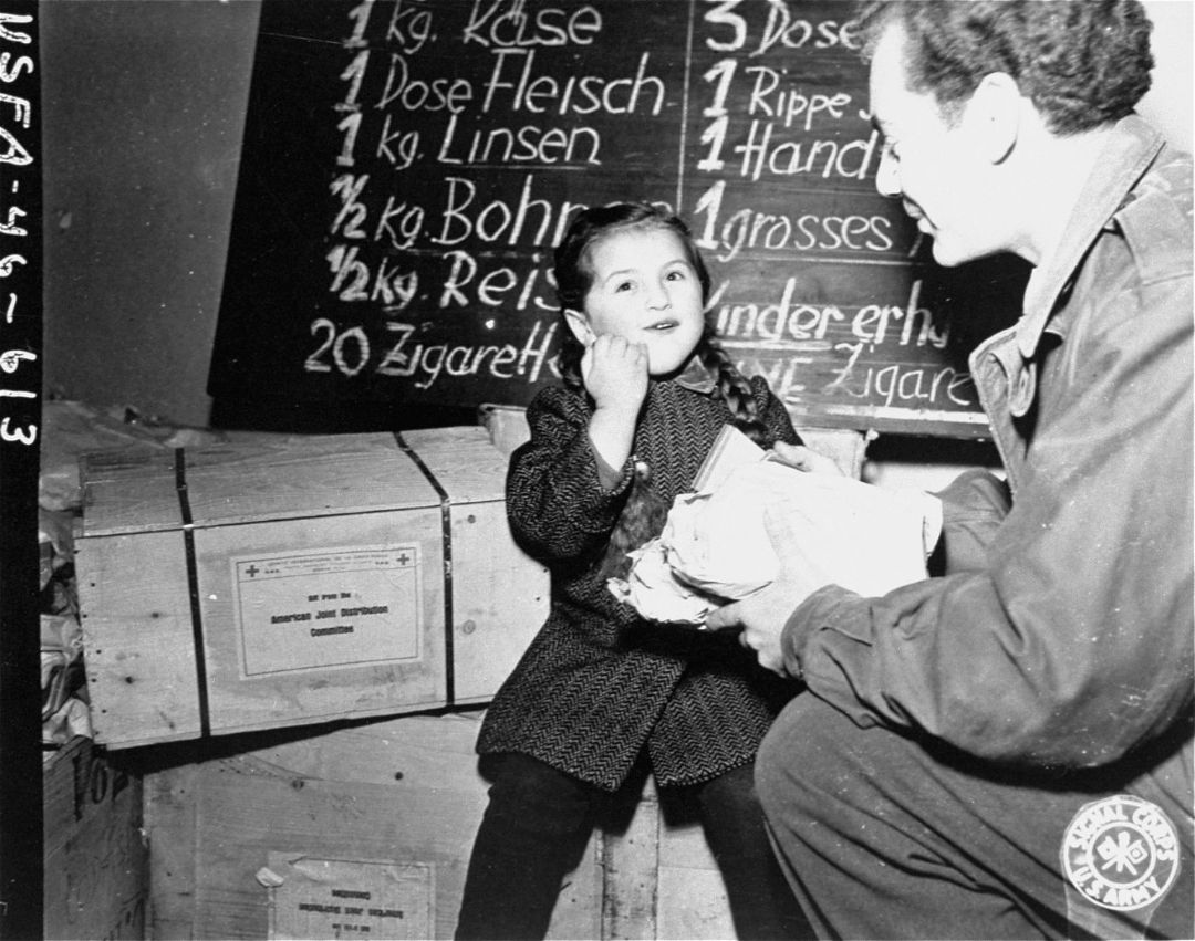 Ein amerikanischer Mitarbeiter des JOINT gibt Lebensmittel an ein j&uuml;disches DP-M&auml;dchen in Wien, 1945/46